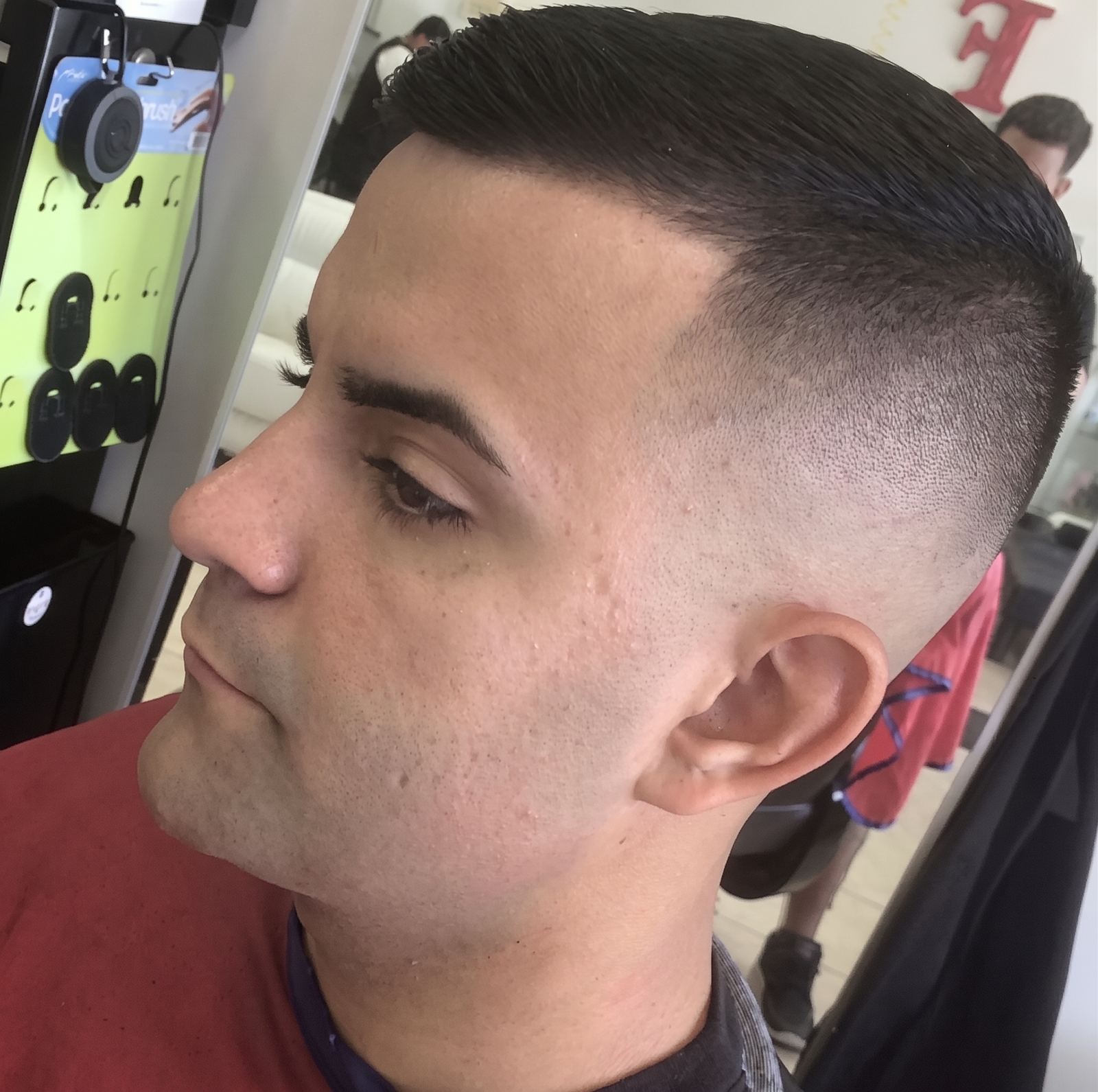 Close side profile of a high skin fade with a hard part cut in above the temple and a sharp lineup across the forehead.